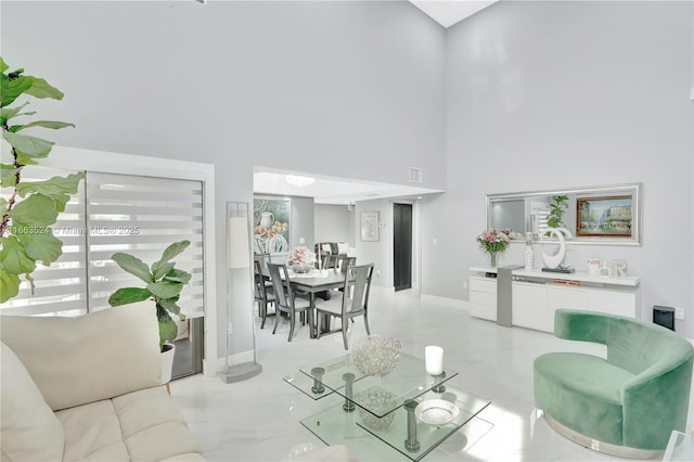 living room with marble finish floor, a high ceiling, visible vents, and baseboards