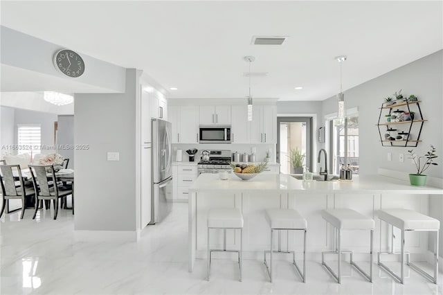 kitchen with appliances with stainless steel finishes, a kitchen bar, a sink, and visible vents