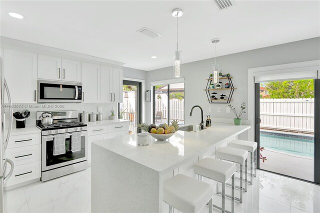 kitchen featuring white cabinetry, appliances with stainless steel finishes, sink, and a center island with sink