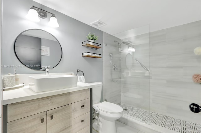 bathroom featuring visible vents, a tile shower, vanity, and toilet