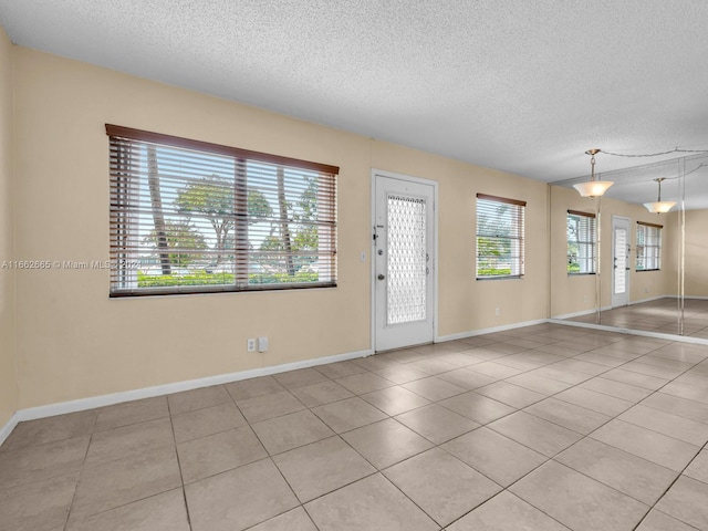 interior space featuring a textured ceiling, light tile patterned floors, and a wealth of natural light