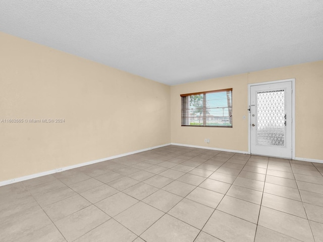 empty room featuring a textured ceiling and light tile patterned flooring