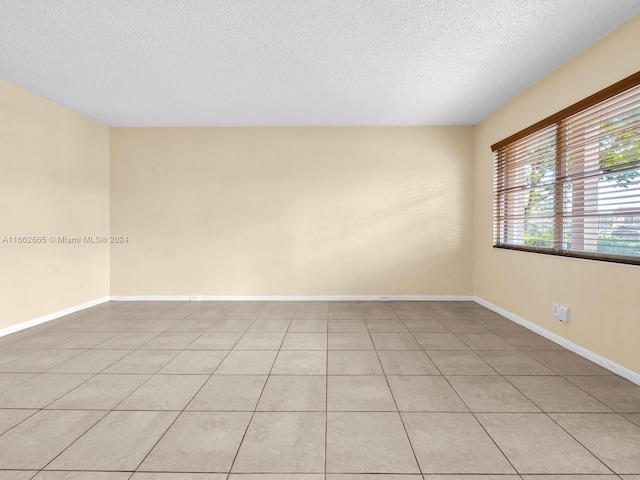 tiled empty room with a textured ceiling