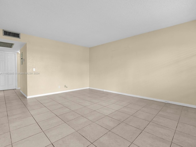 tiled empty room featuring a textured ceiling