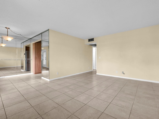 spare room featuring a textured ceiling and light tile patterned flooring