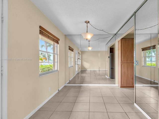 corridor featuring a textured ceiling and light tile patterned floors