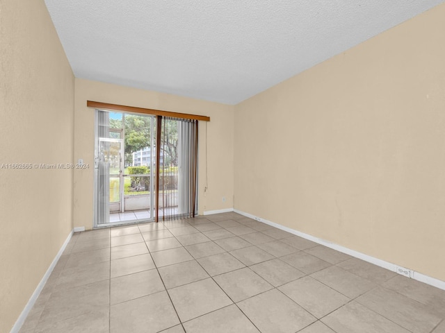 tiled empty room with a textured ceiling