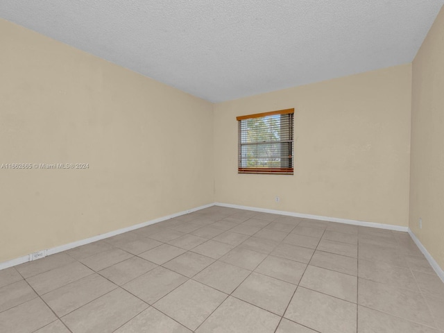 empty room featuring a textured ceiling and light tile patterned flooring