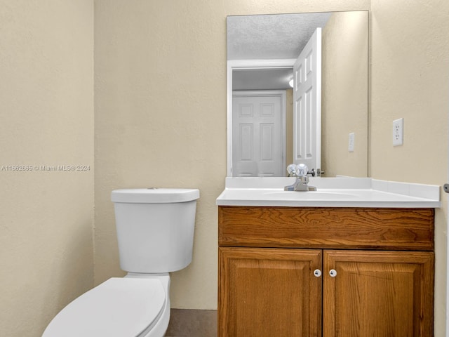 bathroom featuring a textured ceiling, vanity, and toilet