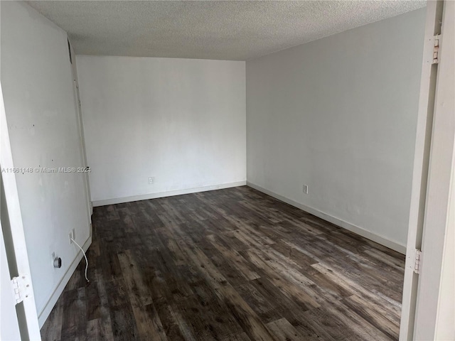 empty room featuring a textured ceiling and dark hardwood / wood-style flooring