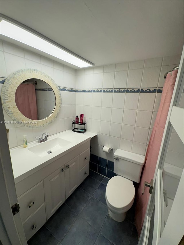 bathroom with tile walls, curtained shower, vanity, toilet, and tile patterned floors