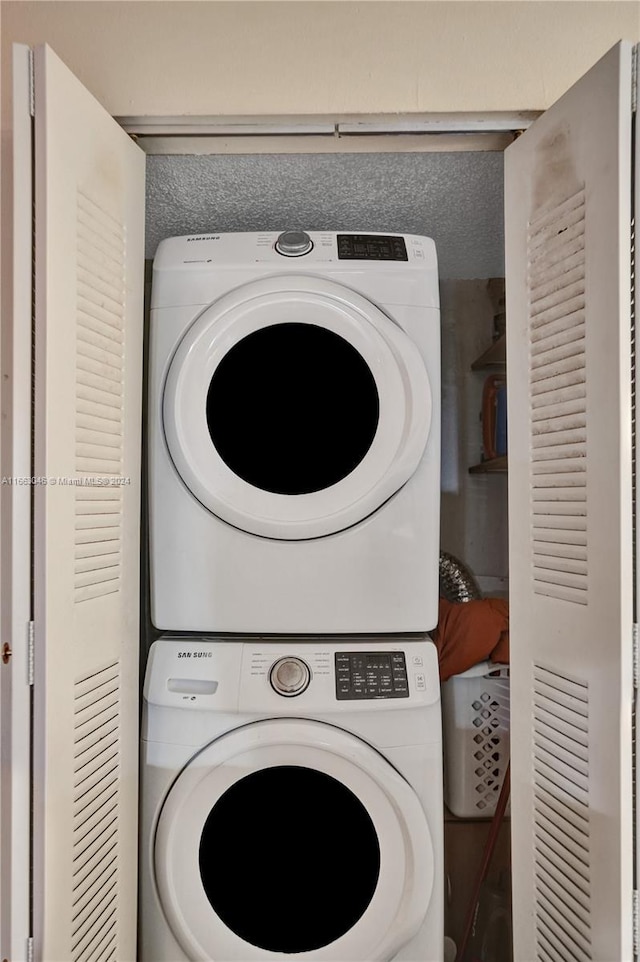 clothes washing area with stacked washing maching and dryer