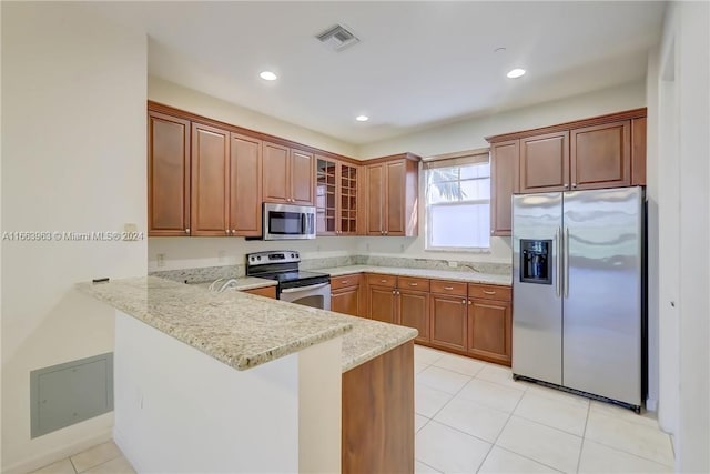 kitchen with light stone countertops, stainless steel appliances, kitchen peninsula, and light tile patterned floors