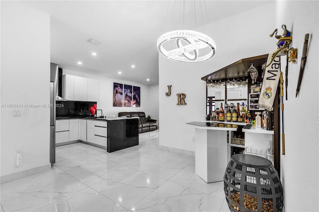 kitchen featuring sink, white cabinets, kitchen peninsula, decorative backsplash, and decorative light fixtures