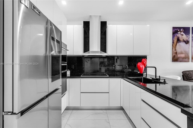 kitchen with white cabinets, wall chimney exhaust hood, stainless steel fridge, and sink