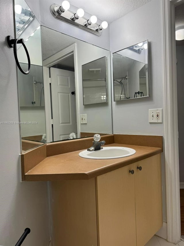 bathroom with tile patterned flooring, a textured ceiling, and vanity