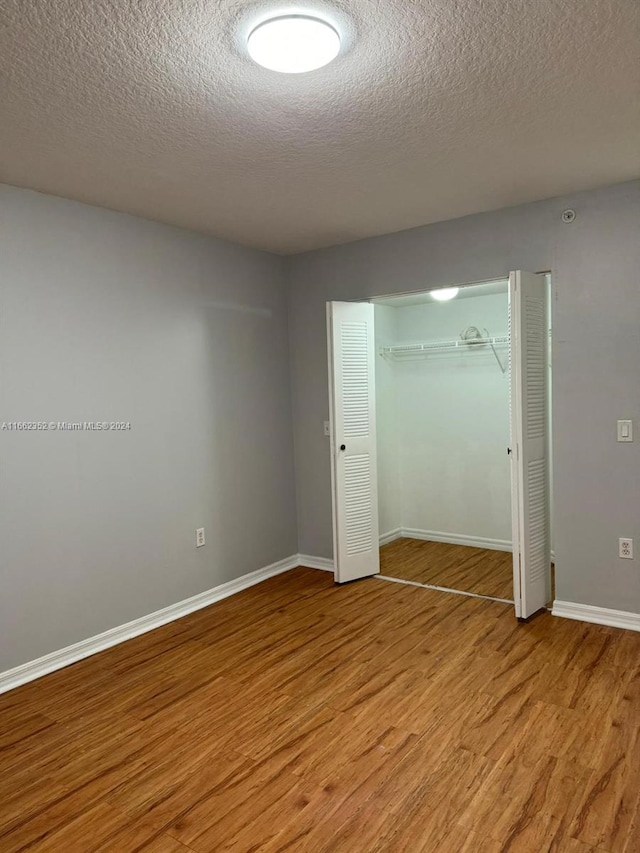 unfurnished bedroom with a textured ceiling, a closet, and light hardwood / wood-style floors