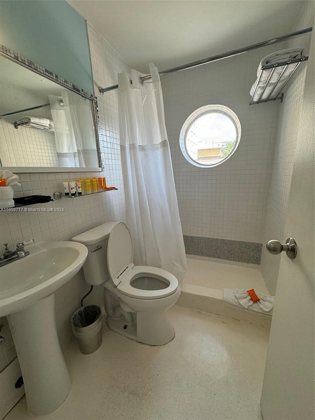 bathroom with tile walls, curtained shower, backsplash, toilet, and sink