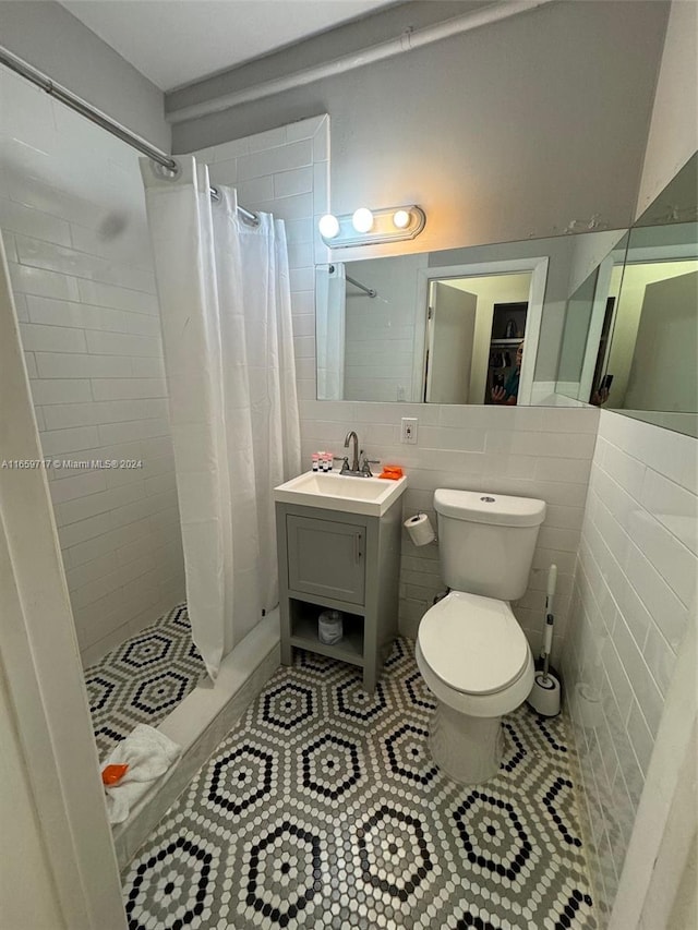 bathroom with tile walls, tile patterned flooring, curtained shower, vanity, and toilet