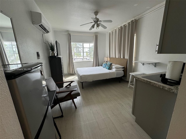 bedroom with ceiling fan, a textured ceiling, light hardwood / wood-style floors, and a wall mounted AC