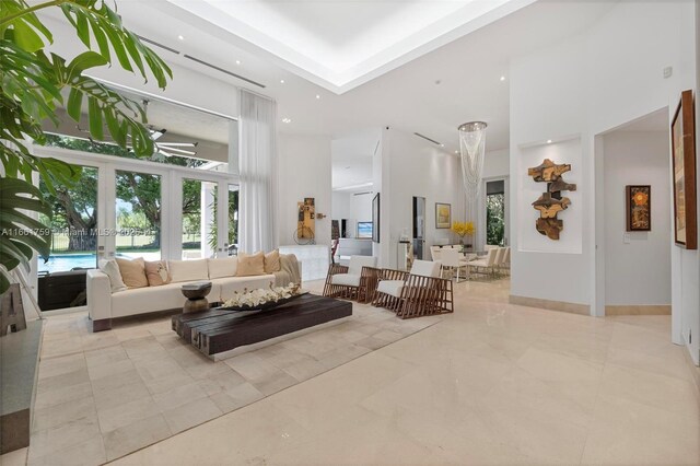 living room featuring a high ceiling, a raised ceiling, a fireplace, and a chandelier