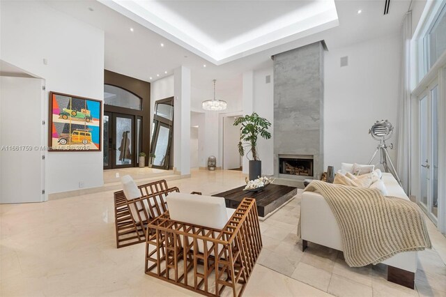 living room featuring french doors, a high ceiling, an inviting chandelier, and a fireplace