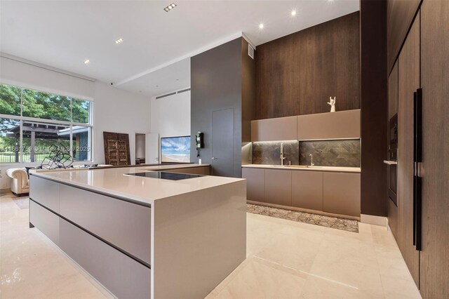 kitchen featuring black electric cooktop, hanging light fixtures, kitchen peninsula, and a notable chandelier