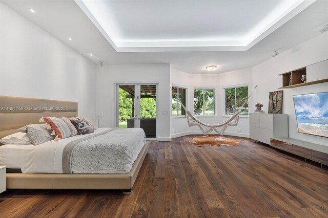 bedroom with a raised ceiling, dark hardwood / wood-style floors, and access to exterior