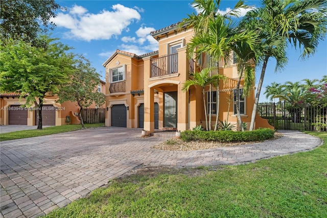 mediterranean / spanish home with a balcony, a front lawn, and a garage