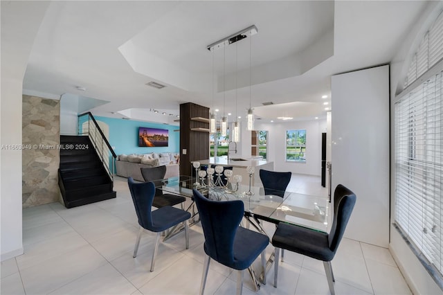 dining space with light tile patterned floors, a raised ceiling, and sink