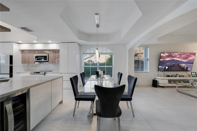 tiled dining space with a raised ceiling and wine cooler