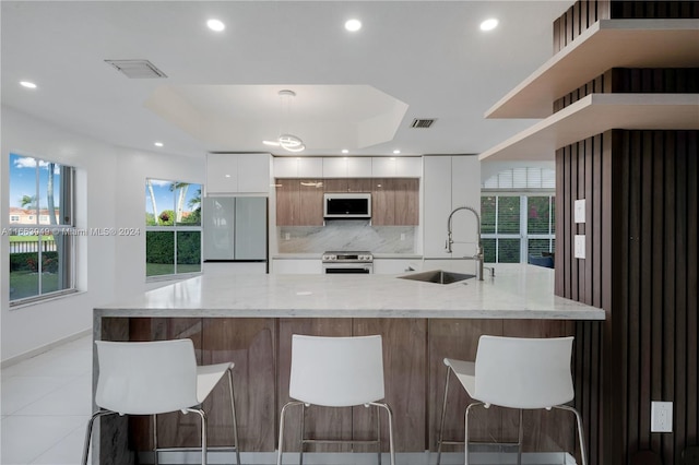 kitchen with white cabinetry, appliances with stainless steel finishes, a spacious island, and sink