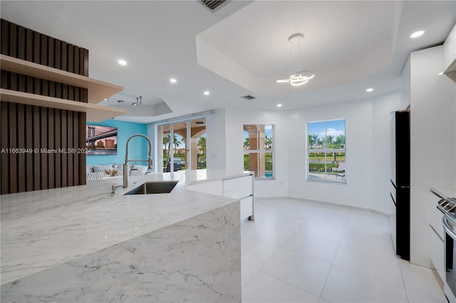 kitchen featuring white cabinets, light stone counters, decorative light fixtures, and sink