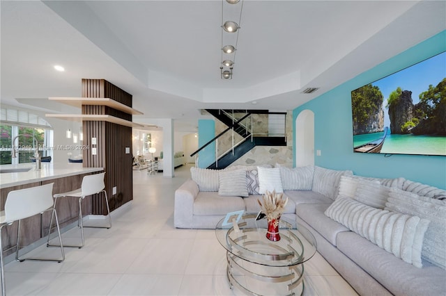 living room with a tray ceiling and sink