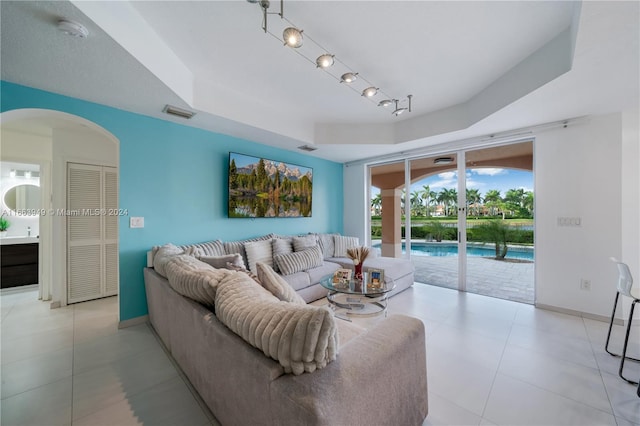 living room with rail lighting and a tray ceiling