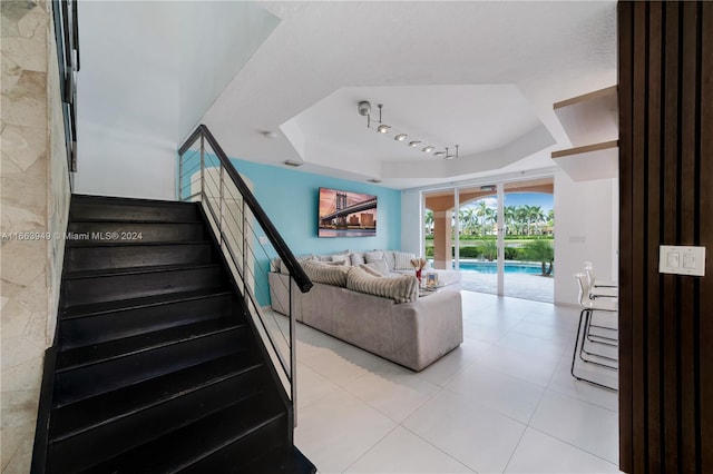 living room featuring a tray ceiling and rail lighting