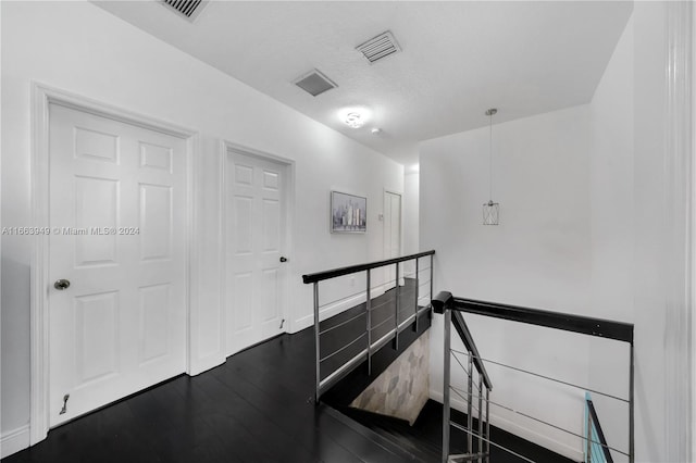 hall with a textured ceiling and dark hardwood / wood-style flooring