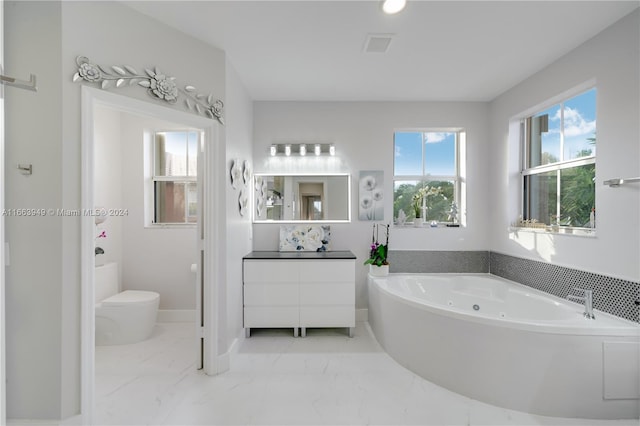 bathroom with vanity, toilet, and a tub