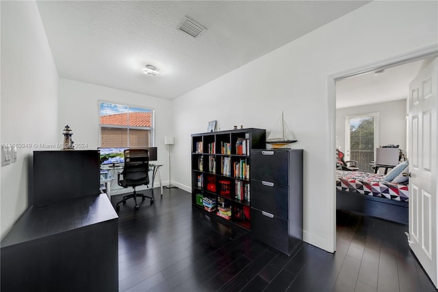 home office with a textured ceiling and dark wood-type flooring