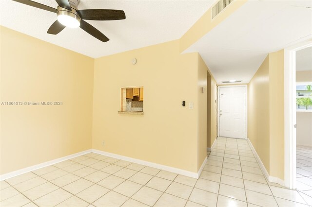 unfurnished room featuring ceiling fan, light tile patterned floors, and a textured ceiling