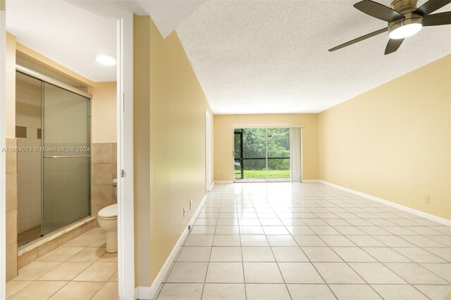 empty room featuring ceiling fan, light tile patterned flooring, and a textured ceiling