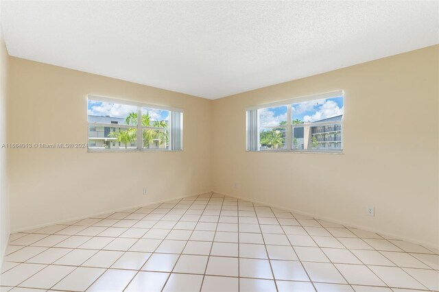 tiled spare room featuring a textured ceiling