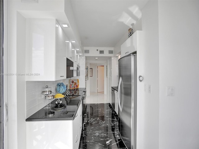 kitchen featuring decorative backsplash, stainless steel appliances, and white cabinets