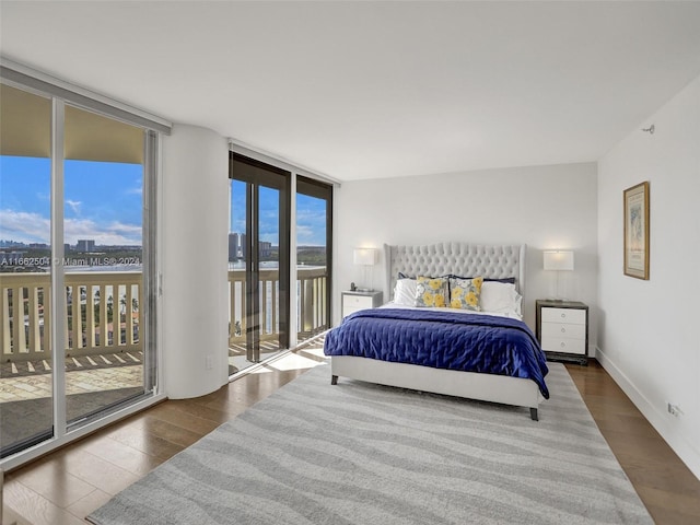 bedroom with access to outside, dark wood-type flooring, and expansive windows