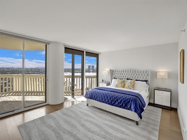 bedroom with light wood-type flooring, access to outside, and floor to ceiling windows