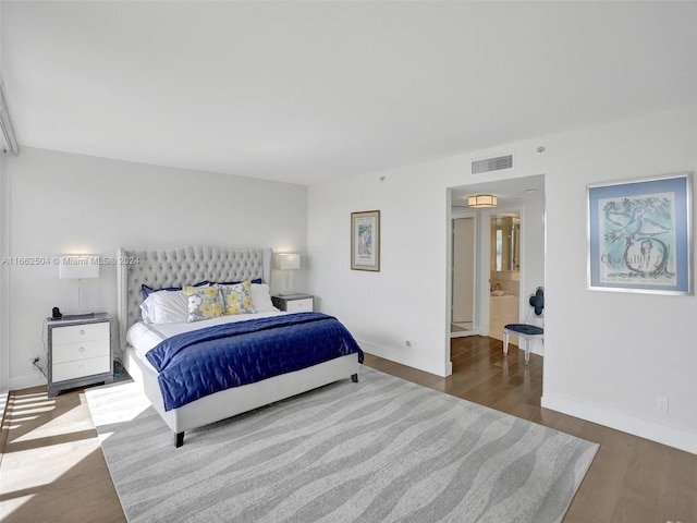 bedroom featuring hardwood / wood-style flooring and connected bathroom