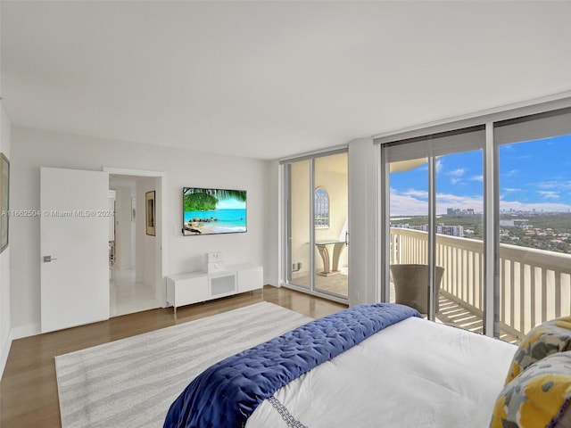 bedroom with hardwood / wood-style flooring, a wall of windows, and access to exterior