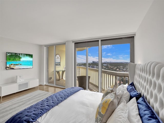 bedroom featuring wood-type flooring, expansive windows, and access to exterior