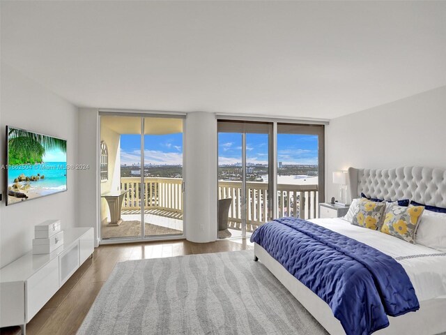 bedroom with floor to ceiling windows, access to exterior, and hardwood / wood-style floors