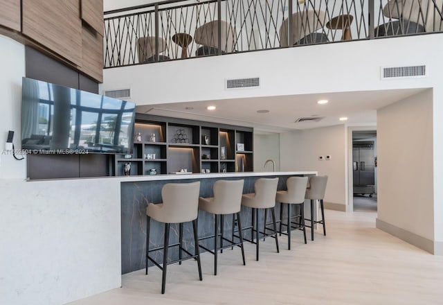 kitchen with a towering ceiling, light wood-type flooring, and sink